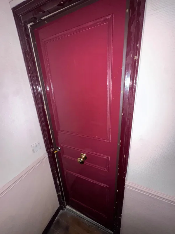 Porte palière bordeaux avec bouton laiton et serrure remplacée